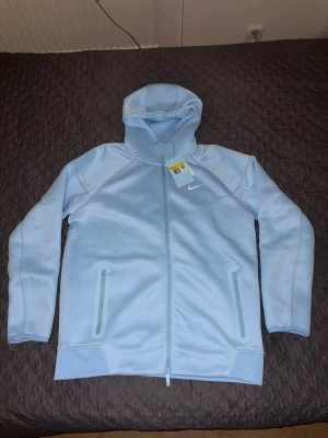 Babyblå zip från Nike Nocta - Babyblå zip up från Nike NOCTA. Den är i storlek S och passar egentligen perfekt men är liiite kort i armarna på mig. Tröjan har huva och en liten vit Nike logga på bröstet. Perfekt för dig som gillar sportig och clean stil. Hör gärna av er om ni har några frågor! Pris kan diskuteras😁👌