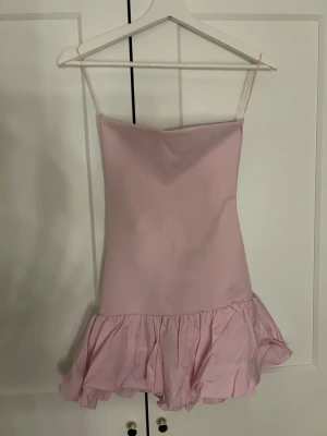 Rosa kort klänning med volang - Söt rosa klänning tube klänning med volang nedtill. Klänningen är ärmlös och har en enkel, figurnära passform som ger en feminin look. Aldrig använd💓