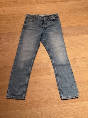 Blå raka jeans från Jack & Jones - Klassiska blå jeans från Jack & Jones i rak modell. Jeansen har en bakficka med diskret söm och en brun läderpatch med logga i midjan. Tillverkade i slitstarkt denimtyg som ger en tidlös look. Modell Loose / Chris. Stl 30/30.