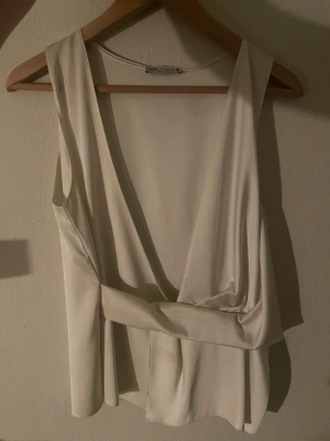 Vit omlottopp från Zara - Super snygg vit satin omlottopp från Zara med djup v-ringning och bred knytdetalj i midjan.