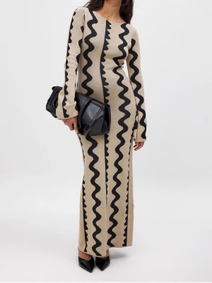 Beige långklänning med svart mönster - Trendig beige långklänning med svarta vågiga ränder. Klänningen har lång ärm, rund halsringning och figurnära passform. Tillverkad i ett mjukt stickat material som ger en bekväm känsla och cool look.