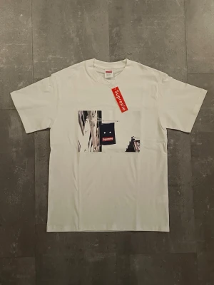 Supreme Banner Tee White FW23 – Flag Print – Size S - • Vit t-shirt med ikoniskt flagg/byggnad-print framtill • 100% bomull – klassisk Supreme passform • Skick: [ange t.ex. 9/10, använd få gånger] • Inga hål, inga hål  Säljer pga: Används inte Skickas snabbt 📦 Pris kan diskuteras vid snabb affär. 