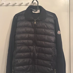 Monclear cardigan  - Säljer en snygg svart pufferjacka från Moncler i mycket bra skick. Jackan har en dragkedja framtill och långa ärmar. Perfekt för höst och vinter med sin quiltade design som håller dig varm. Den har en stilren look med Moncler-loggan på ärmen. Passar både till vardags och lite finare tillfällen. Pris kan diskuteras.