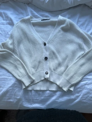 Vit ribbstickad kofta från lager 157 -  vit kofta från lager 157 med tre knappar framtill och djup v-ringning💗 säljer för har inte kommit till användning. Har en liten fläck som inte går bort vid knapparna