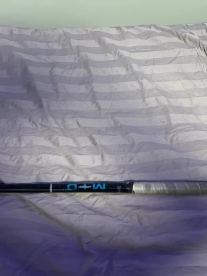Unihoc innebandyklubba svart/vit - Säljer en Unihoc innebandyklubba med svart skaft och vit böjd blad. Skaftet har blå och vita detaljer samt texten 'M D'. Greppet är lindat med ljusgrått greppband. Perfekt för dig som gillar innebandy och vill ha en snygg och funktionell klubba.