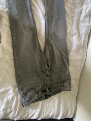Gråa jack and Jones jeans. Slim fit. 33/32  - Säljer ett par grå jeans med rak passform och klassiska fem fickor. Jeansen har diskreta sömmar och en enkel design utan slitningar eller dekorationer. Perfekta för en clean och avslappnad stil.