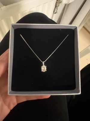 Silverhalsband med klar sten - Elegant halsband från Edblad i silverfärg med en tunn kedja och ett hängsmycke med en klar, gnistrande sten i oval slipning. Kommer i en stilren presentask. 
