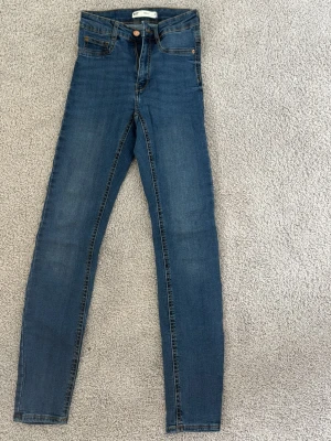 Blå skinny jeans från Gina Tricot - Säljer ett par klassiska blå skinny jeans från Gina Tricot, modell Molly. Jeansen har hög midja.