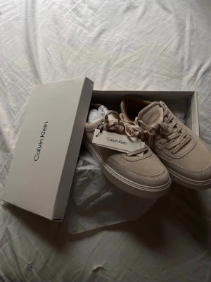  Calvin Klein Beige mocka - Stilrena beige sneakers från Calvin Klein i mocka. Väldigt snygga aldrig nya och allting med box men även lappar och helt par nya skor som aldrig varit andvända. Priset är ej hugget i sten! 