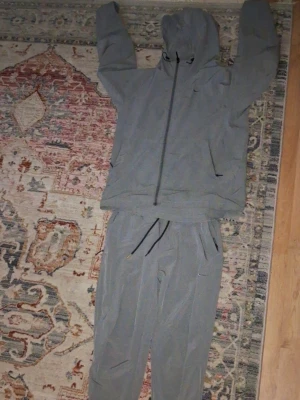 Grå Nike Unlimited Tracksuit - Fett fin bra för sommar, både byxor o tröjan S, Men jackan passar också M,  Finns ett litet hål bredvid loggan på jackan och ett litet större hål på baksidan (Sista bilden) , Allmänt bra tracksuit.