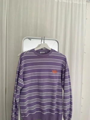 Randig lila sweatshirt - Säljer denna randiga sweatshirt från Junkyard, storlek XS. Den är lite större i storleken :)