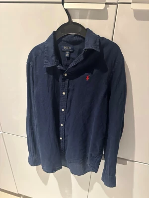 Marinblå linneskjorta från Polo Ralph Lauren - Klassisk marinblå skjorta från Polo Ralph Lauren i linne i storlek XL i barn