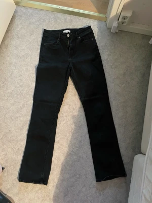 Svarta raka jeans från H&M - Säljer ett par svarta jeans från H&M i rak modell med hög midja. Klassisk femficksdesign och knappgylf. Perfekta till vardagslooken och funkar året runt. Materialet är mjukt och stretchigt för extra komfort. Kommer inte ihåg exakta priset då den är köpt för flera år sen, skulle säga 300kr max. Den är använd men i mycket bra skick. Sista bilderna är en REFERENS inte den riktiga byxan