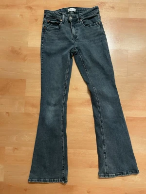 Mörkblå bootcut jeans från Gina Tricot  - Snygga mörkblå bootcut jeans från Levi's med klassisk femficksmodell och hög midja. Jeansen har utsvängda ben och är tillverkade i ett slitstarkt denimtyg. Perfekta för en trendig och avslappnad stil.