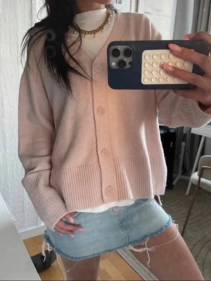 Ljusrosa oversized kofta  - Säljer en ljusrosa oversized kofta med v-ringning och stora knappar framtill. Koftan har ribbade muddar och är gjord i ett mjukt stickat material. Perfekt att slänga över en t-shirt för en chill look.