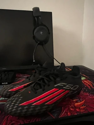 Adidas F50 svarta och röda fotbollsskor - Säljer ett par Adidas F50 fotbollsskor i svart med röda och silvriga detaljer. Skorna har låg profil, snörning och mönstrad ovandel för bättre bollkontroll. Perfekta för dig som vill ha lätta och snabba skor på planen. Använda 6 träningar och 3 matcher 1 månad gammal anledning jag säljer dom e för jag ska sluta. Skriv vid funderingar och mer bilder 😁 nypris 2799 