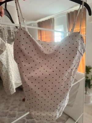 Vit prickig linnetopp med tunna band från Gina tricot  - Söt vit linnetopp med svarta prickar och tunna justerbara axelband. Storlek S, använd 1 gång helt ny 🤍