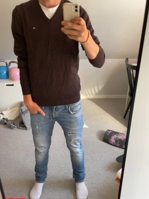 J Lindberg tröja mörkbrun  - Mörkbrun långärmad t-shirt med rund hals och rak passform. Tröjan är enkel utan synliga tryck förutom j lindberg märket på bröstet och har ribbade muddar vid ärmslut och nederkant. Materialet är väldigt mjukt och bekvämt, troligen bomull.