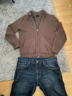  ziptröja från Massimo Dutti  - Mörkblå jeans med raka ben och klassisk femficksdesign. Jeansen har kontrastsömmar och en knappgylf. Materialet ser ut att vara slitstark denim i bomull. Passar perfekt till en avslappnad stil och är lätta att matcha med olika överdelar.