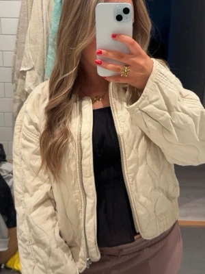 Beige quiltad cardiganjacka från mango - Snygg beige quiltad cardiganjacka från MNG med dragkedja framtill och lätt oversized passform. Perfekt att slänga över en topp för en trendig look. Väldigt eftertraktad 