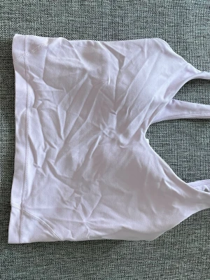Ljuslila sport-bh från Lululemon - Säljer en ljuslila sport-bh från Lululemon med breda axelband och mjukt, stretchigt material. Perfekt för träning och yoga. 