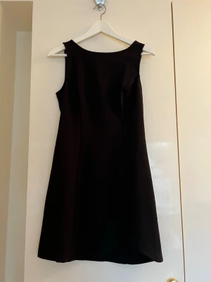 Svart kortklänning - Klassisk svart ärmlös klänning med rund halsringning och lätt utställd kjol. Enkel och stilren design som passar perfekt till många olika tillfällen. Dragkedja i ryggen för enkel påklädning.