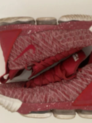 Röda Nike LeBron high sneakers - Säljer ett par röda Nike LeBron sneakers med stickad ovandel och vita detaljer. Skorna har högt skaft, grova röda skosnören och synlig dämpning i sulan. Perfekta för dig som gillar basketstil och vill sticka ut med en sportig look.