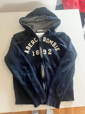 Abercrombie & fitch zip hoodie mörkblå  - Riktigt snygg och eftertraktad Abercrombie zip hoodie i mörkblå färg. Fint skick inga fel storlek M. Pris endast 488kr kom gärna med frågor och prisförslag har även mer i min profil rabatt vid flera såklart ✌️😁