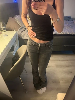 Grå bootcut jeans med låg midja - Snygga grå jeans med bootcut-modell och medelhög midja. Jeansen har klassisk femficksdesign och dragkedjegylf. Perfekta för dig som gillar en avslappnad men trendig stil.