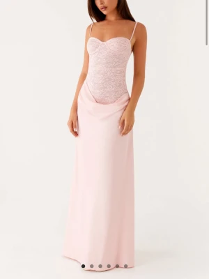 Ljusrosa långklänning med spetsliv - Elegant ljusrosa långklänning med smala axelband och figurnära spetsliv. Kjolen är slät och faller mjukt ner till golvet. Perfekt för dig som vill ha en romantisk och feminin look. Ny med alla prislappar kvar.