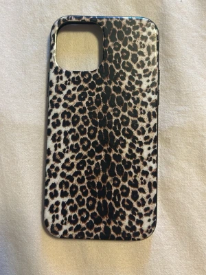 Leopardmönstrat mobilskal iPhone 12 - Snyggt mobilskal med leopardmönster i brunt, svart och beige. Skalets form är slim och det har en stor öppning för kameran. Tillverkat i plast som skyddar mobilen mot repor och stötar. Perfekt för dig som vill ha en trendig look på mobilen.