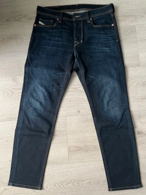 Mörkblå jeans från Diesel - Snygga mörkblå jeans från Diesel med klassisk femficksdesign och kontrastsömmar. Jeansen har rak passform. Perfekta för en avslappnad och stilren look.