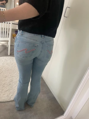 Ljusblå bootcut jeans med brodyr - Nelly jeans med rosa detaljer, skit snygga. Dom är använda 4 gånger. Storlek S! Dom är lågmidjade