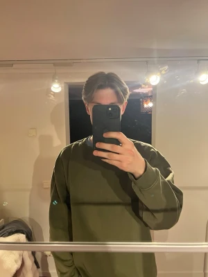 Olivgrön sweatshirt från Weekday - En stilren olivgrön sweatshirt från Weekday med rund halsringning och ribbade muddar vid ärmslut och nederkant. Tröjan har en relaxed fit och är tillverkad i mjuk bomull, perfekt för en avslappnad look.