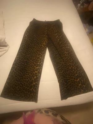 Leopardmönstrade mjukisbyxor - Säljer ett par mjukisbyxor med leopardmönster i bruna och svarta toner. Byxorna har breda ben och resår i midjan för extra komfort. Perfekta för dig som vill ha en trendig och avslappnad look.