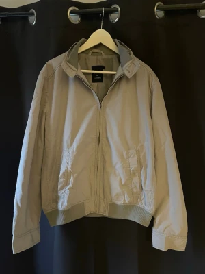 J.Lindeberg jacka  - Tja!Säljer en snygg ljusgrå/beige vindjacka med vita snören ifrån J.Lindeberg. Jackan har ribbade muddar och midja, dragkedja framtill och fickor på sidorna. . Perfekt för dig som gillar stilren och clean look nu till våren. Storlek L passar M jag på bilden är ish 180cm. Skick 10/10🤩hör av dig vid minsta lilla fundering eller fråga🙌🏼mvh premium fashion