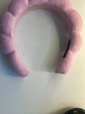 Rosa vadderat diadem - Ett fluffigt, vadderat diadem i ljusrosa tyg med flätad design. Perfekt för att ge en söt och trendig touch till din look. Diademet är mjukt och bekvämt att bära hela dagen.