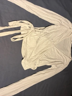 Beige omlottkofta från 157 - Säljer en beige omlottkofta från 157 i storlek XS. Koftan har långa ärmar och knyts i midjan med ett band. Tunt och mjukt material som passar perfekt till lager på lager och ger en avslappnad look.