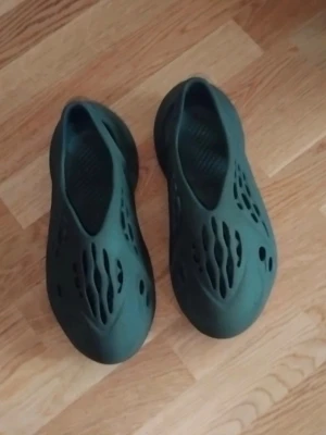 Mörkgröna foam tofflor med hålmönster - Säljer ett par svarta Adidas tofflor  har bara andvänds några gånger