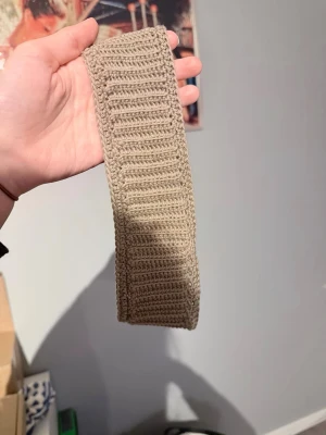 Grått virkad hårband - Säljer ett grått virkat hårband i mjukt garn. Hårbandet är brett och elastiskt, perfekt för att hålla håret på plats. Snyggt ribbat mönster som ger en trendig och enkel look. Passar till många olika frisyrer och stilar.