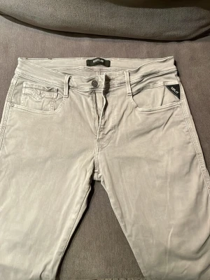 Ljusgrå jeans från Replay - Snygga ljusgrå jeans från Replay med klassisk femficksmodell och smal passform. Jeansen har diskreta sömmar och Replay-logga på fickan. Tillverkade i mjukt denimtyg som ger en bekväm känsla och stilren look. Inte så ofta använda så där av riktigt bra skick.