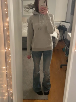 Grå/beige hoodie från Peak Performance - Säljer en stilren grå/beige hoodie från Peak Performance med broderad logga på bröstet. Hoodien har huva med dragsko, magficka och ribbade muddar vid ärmslut och nederkant. Perfekt för en avslappnad och sportig look.