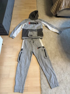 Grå Hoodrich tröja och byxor  dress i storlek XL 13-15 år. - Säljer grå Hoodrich dress med svarta och vita detaljer.