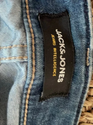 Ljusblå jeans från Jack & Jones - Säljer ett par ljusblå jeans från Jack & Jones Jeans Intelligence. Klassisk femficksmodell med snygga kontrastsömmar. Perfekta för dig som gillar en avslappnad och trendig stil. Materialet är denim i bomull.