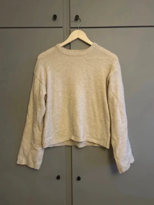 Beige stickad tröja från Gina Tricot - Mysig beige stickad tröja från Gina Tricot med rund halsringning och ribbade muddar. Tröjan har en avslappnad passform och är perfekt för lager-på-lager-stil. Enkel och stilren design som passar till det mesta.