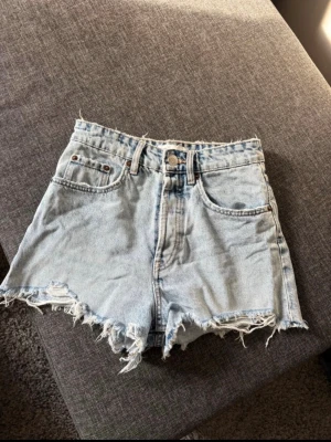 Ljusblåa jeansshorts med fransig kant - Säljer ett par ljusblåa jeansshorts med låg midja och fransig kant. Skönt material. Inte använd 