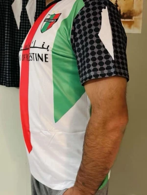 Palestino fotbollströja med tryck - Snygg fotbollströja från Palestino med röd, grön och vit design samt svartmönstrade ärmar. Framsidan har klubbmärke och text, baksidan har tryck med kartor och text på flera språk. Tillverkad i lätt och ventilerande polyester, perfekt för träning eller match.