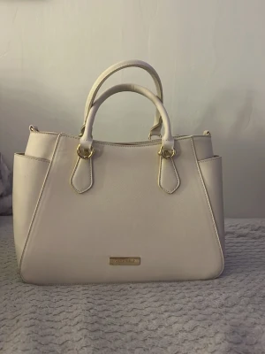 Beige Anna field väska  - Jättefin begie Anna field väska💗När jag har använt den så har det läkt ut lite smink därför den är lite rosa i tyget inuti men inget som färgar av sig. Ska försöka få bort det💗
