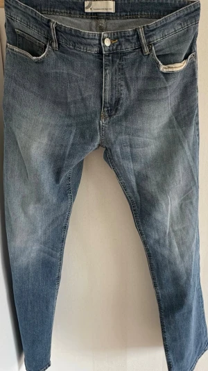 Denim Jeans  - Säljer ett par blå slim fit jeans från Zara med snygga slitningar och tvättade detaljer. Jeansen har klassisk femficksdesign, normal midja och dragkedjegylf. Perfekta för en avslappnad och trendig look.