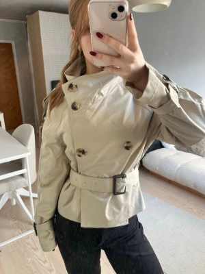 Beige trenchcoat med bälte och knappar - Viral beige kort trenchcoat, super snygg och perfekt till kallare sommarnätter! 😊